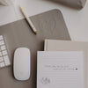 Detail graue Schreibtischunterlage mit Herz-Prägung, Maus und Stift im minimalistischen Design