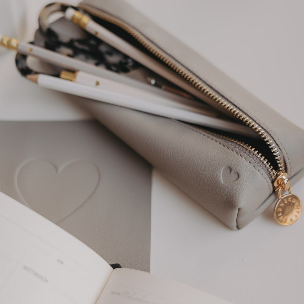 Graue Federtasche von Eulenschnitt mit Herzprägung, geöffnet mit Stiften und Schere im Inneren