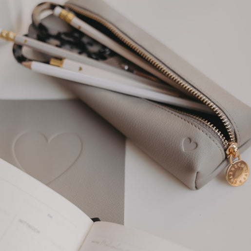 Graue Federtasche von Eulenschnitt mit Herzprägung, geöffnet mit Stiften und Schere im Inneren