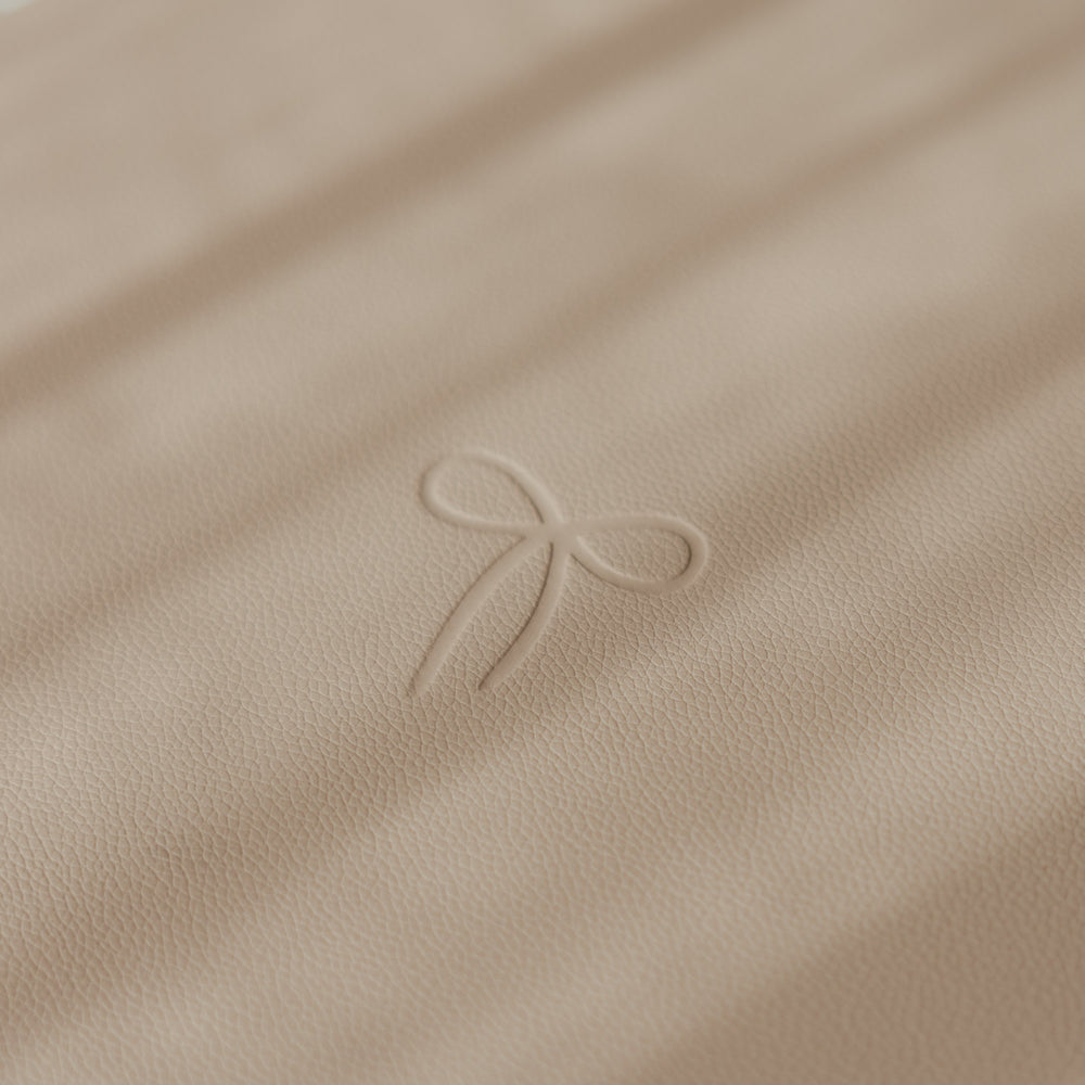 Detailansicht des beigen Platzsets mit feiner Struktur und geprägter Schleife