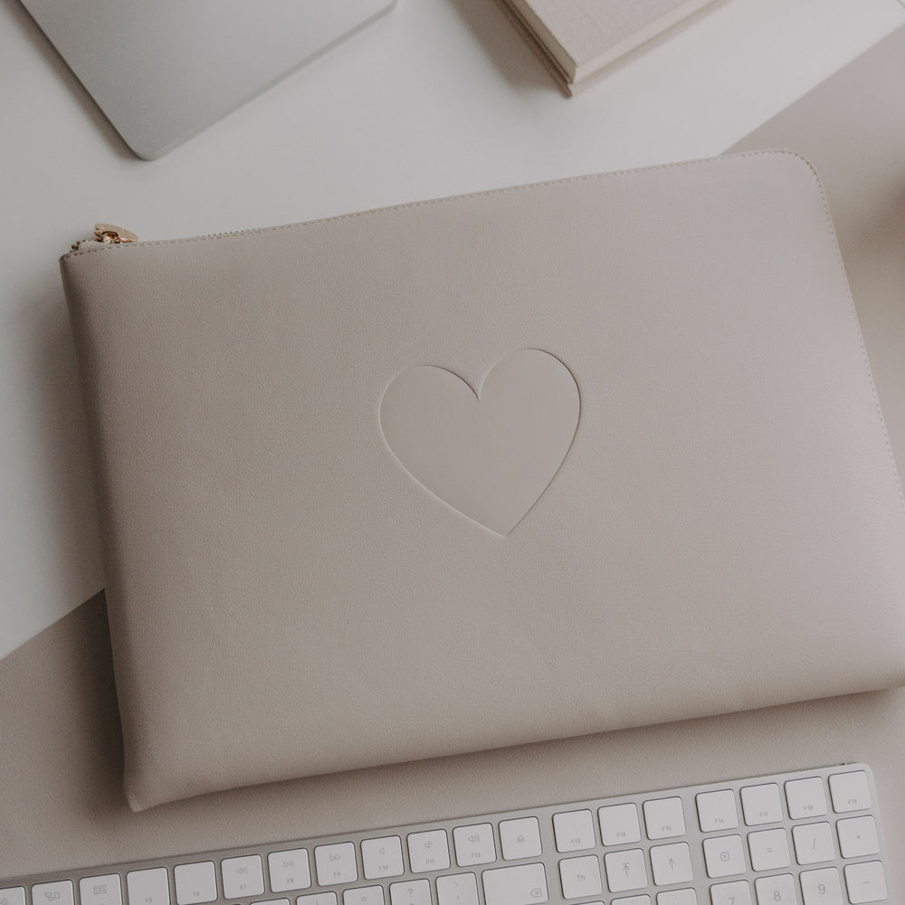 Laptophülle Taupe mit Herzprägung auf Schreibtisch neben Laptop und Tastatur