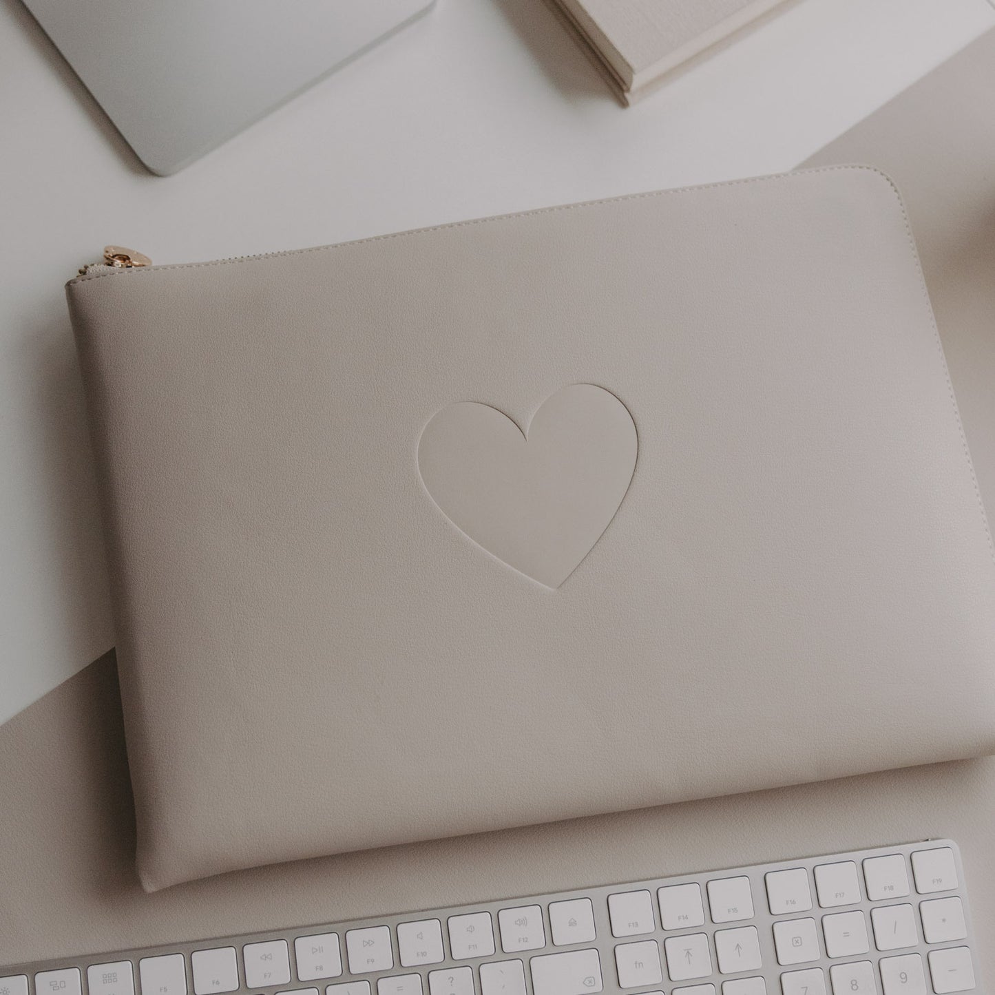 Laptophülle Taupe mit Herzprägung auf Schreibtisch neben Laptop und Tastatur