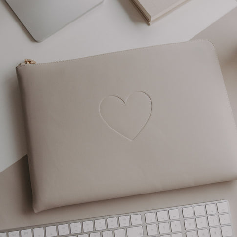 Laptophülle Taupe mit Herzprägung auf Schreibtisch neben Laptop und Tastatur