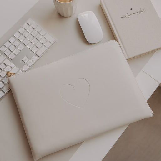 Laptophülle Creme mit Herzprägung auf Schreibtisch mit Tastatur, Maus und Notizbuch
