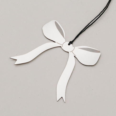 Nahaufnahme des Schleifenanhängers in Silber mit schwarzem Band, auf hellem Hintergrund fotografiert.