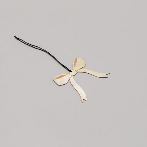 Goldene Schleife aus Metall in schräger Perspektive, filigran gearbeitet mit schwarzer Aufhängung.