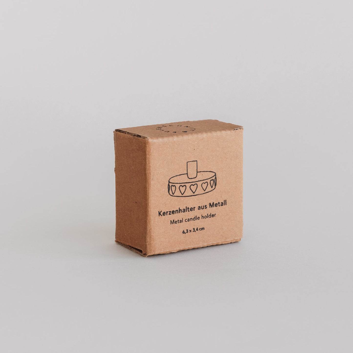 Produktverpackung (Vorderseite):
Verpackung des schwarzen Kerzenhalters mit geprägten Herzen und Illustration.