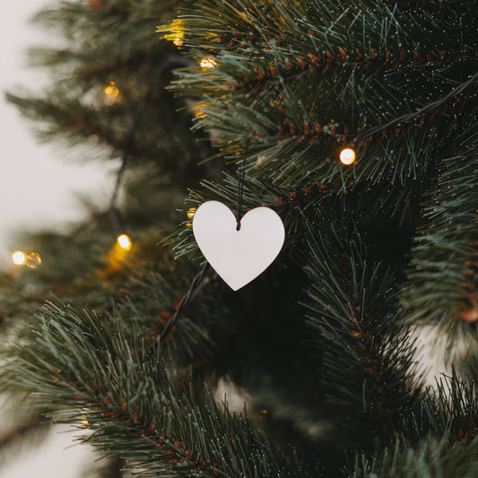 Silberner Herzanhänger am Weihnachtsbaum mit Lichterkette – festliche Dekoration 