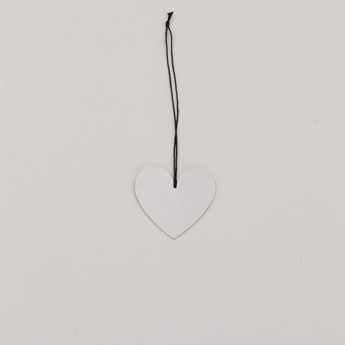 Metallanhänger in Herzform, silbern glänzend, mit schwarzer Kordel auf hellem Hintergrund