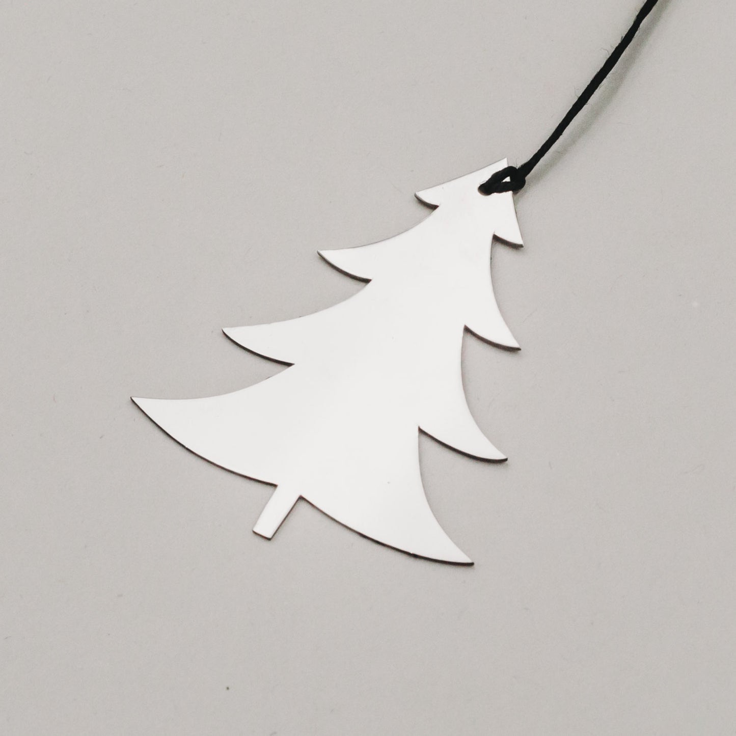 Detailaufnahme von silberner Metalltanne mit schwarzer Schnur, zeigt reflektierende Oberfläche.