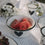 Weiße Emaille-Schale mit schwarzem Herz, gefüllt mit Wassermelonenstücken, im Picknick-Setting.