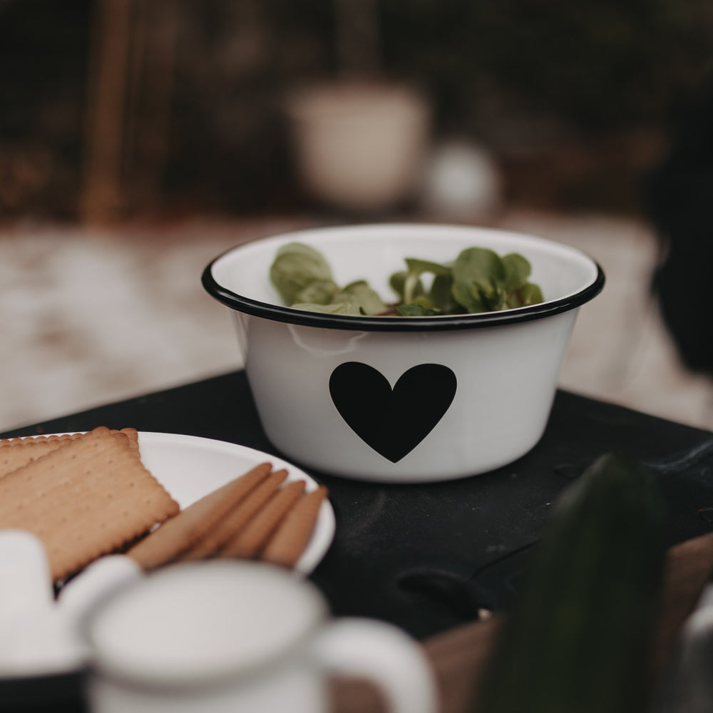 Emaille Schale Herz in Off-White mit Salat, stilvoll dekoriert auf einem Tisch beim Outdoor-Essen.