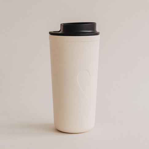 Freigestellter To-go Becher Herz creme mit schwarzem Deckel, schlichtes Design.