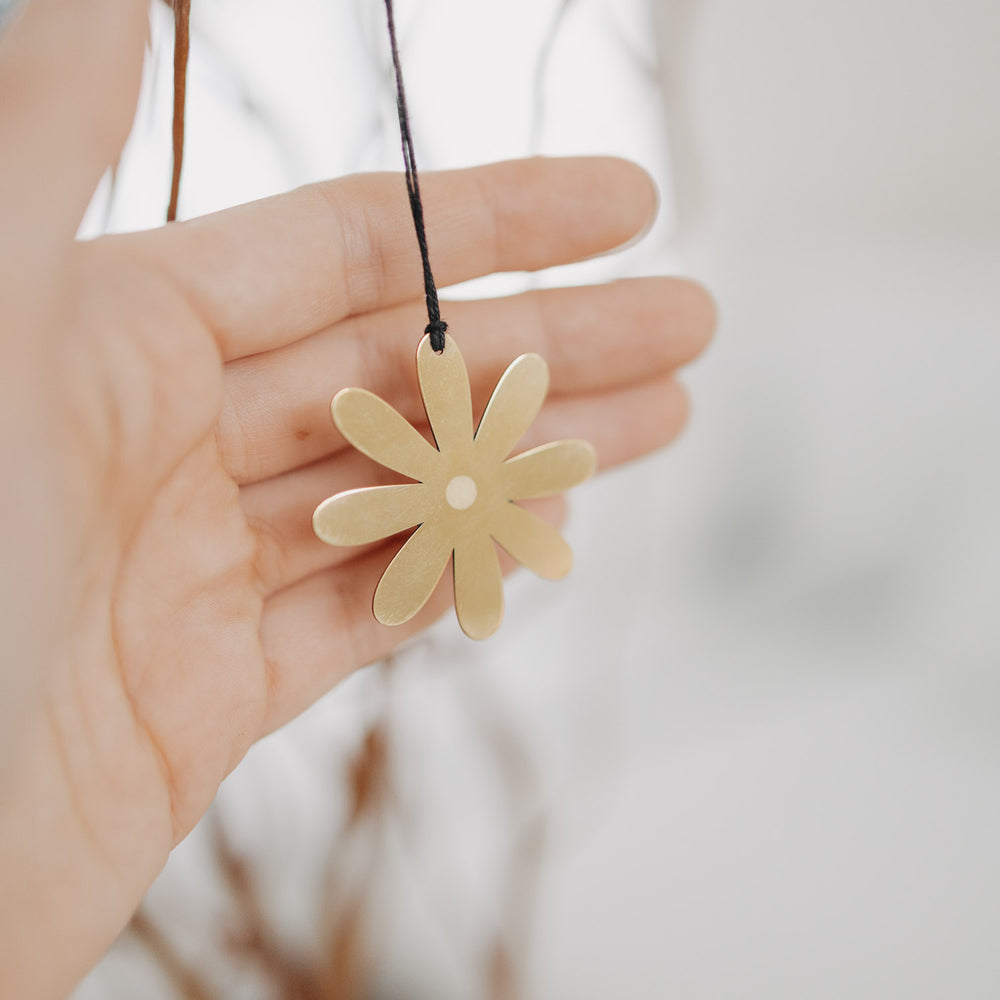 Goldener Metallanhänger Blume in der Hand – filigrane Osterdekoration.