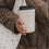 Frau mit cremefarbenem To-Go-Becher mit Herzmotiv und Stofftasche 