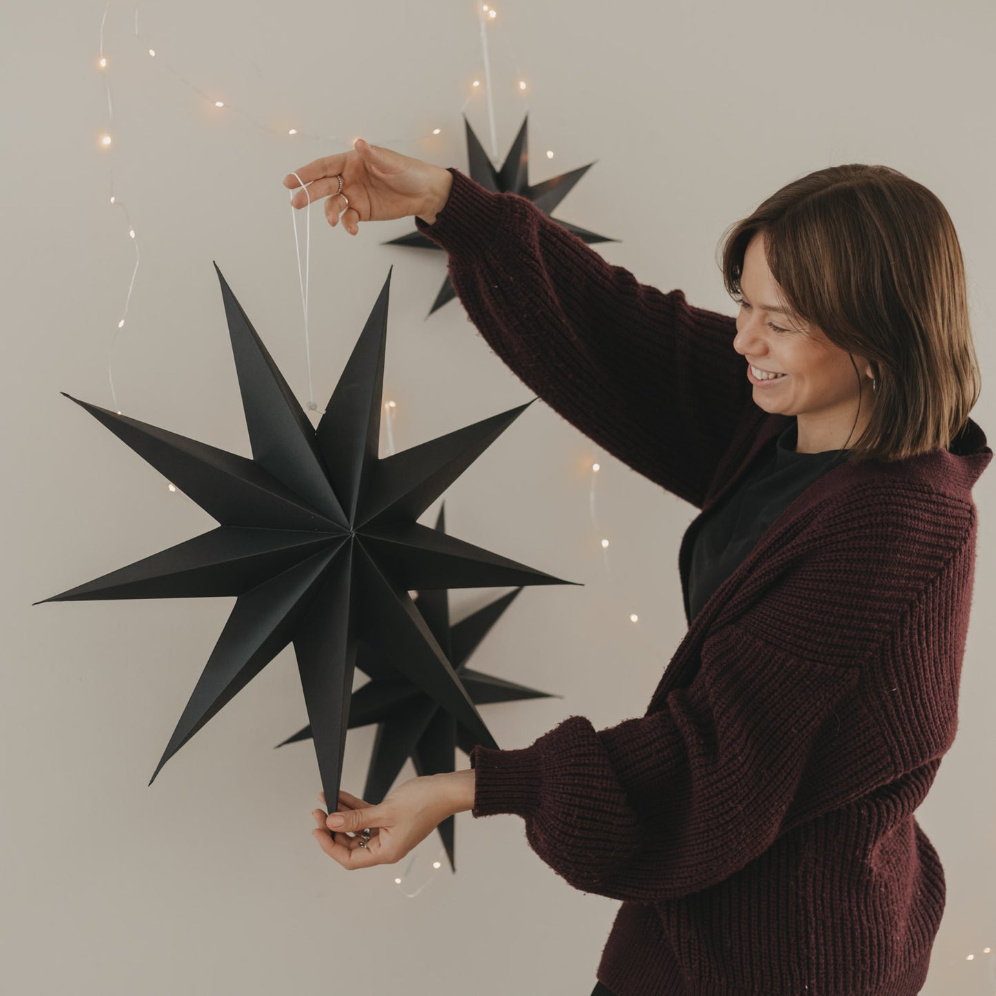 Großer schwarzer Papierstern mit Aufhängung und Lichterkette als moderne Weihnachtsdekoration