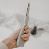 Grauer Papierhase im Aufbau, seitlich gehalten, zeigt die flache Form vor dem Auffalten.