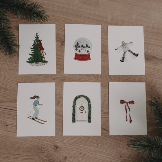 Sechs Weihnachtskarten aus dem Set "Christmas Love" mit winterlichen Motiven auf hellem Holz und Tannenzweigen