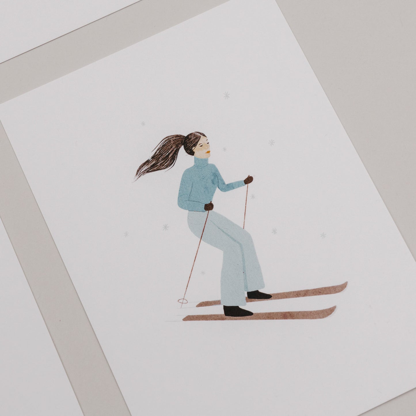 Weihnachtskarte mit einer Frau auf Skiern in blauer Winterkleidung vor weißem Hintergrund
