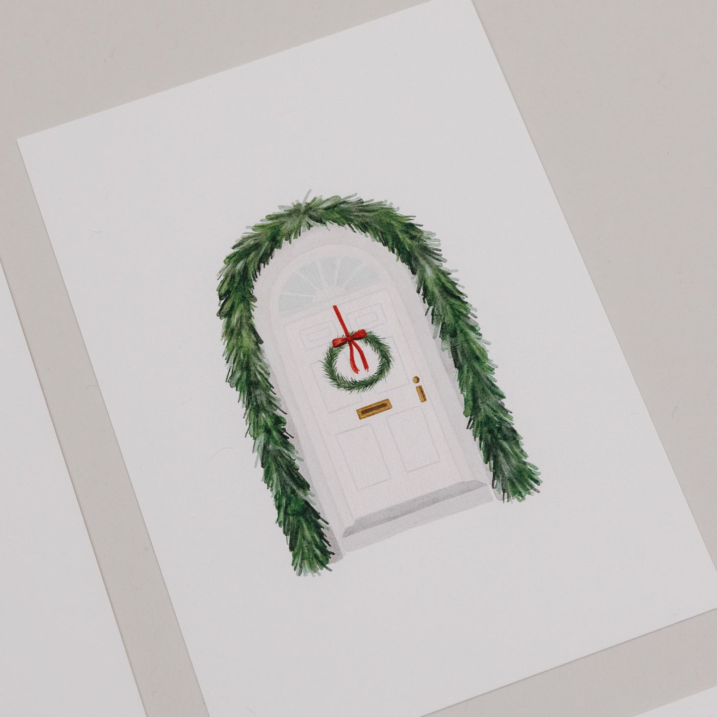 Weihnachtskarte mit weißer Tür, geschmückt mit grünem Türkranz und Tannengirlande