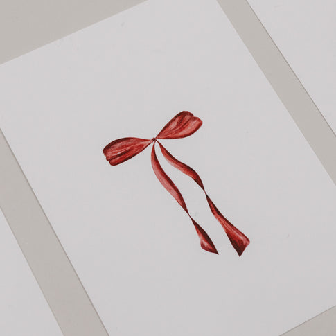 Minimalistische Weihnachtskarte mit roter Schleife auf weißem Hintergrund