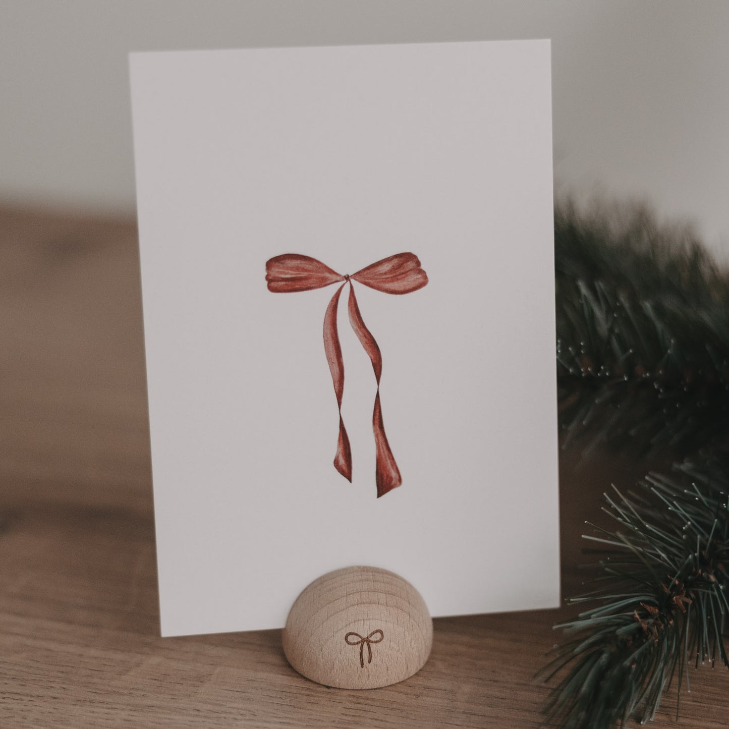 Minimalistische Weihnachtskarte mit roter Schleife auf weißem Hintergrund