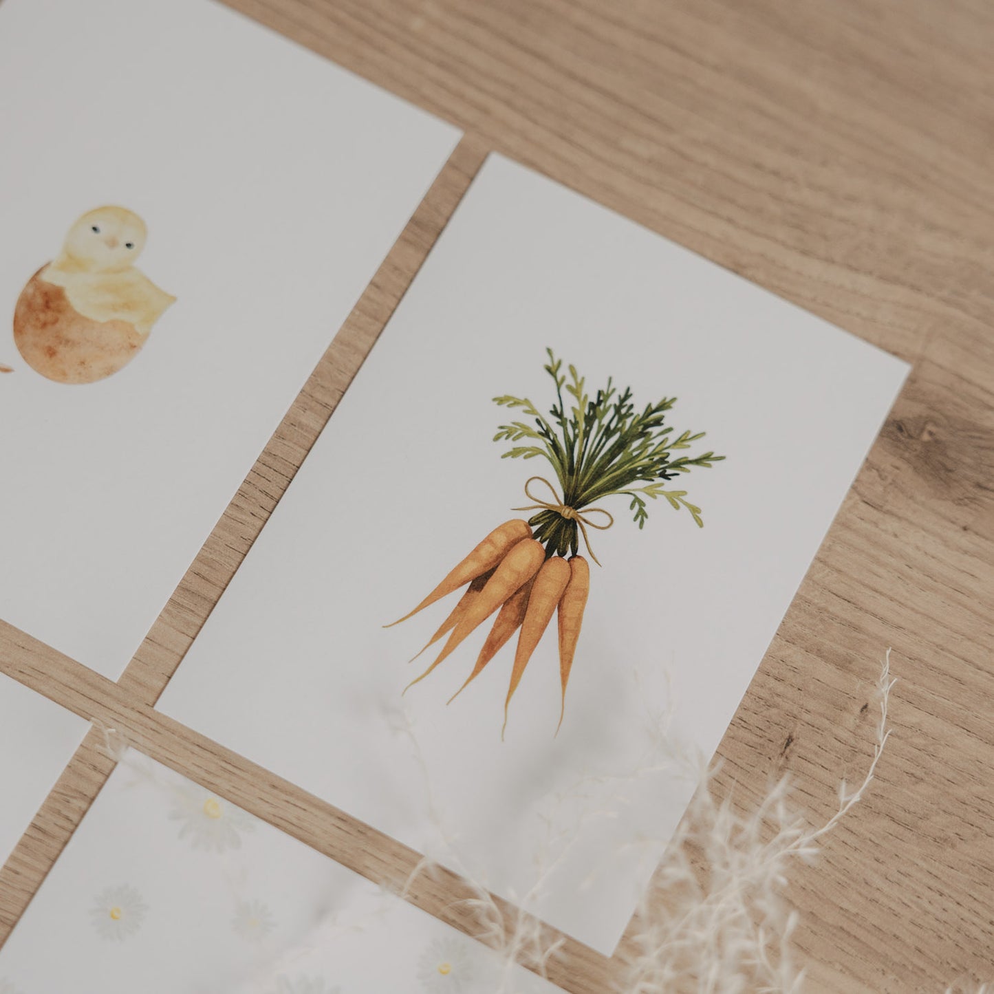 Aquarellkarte mit Möhrenmotiv, auf Holztisch mit Frühlingsdeko platziert.