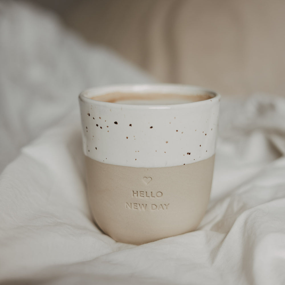 Keramikbecher „Hello New Day“ in Beige und Weiß mit Herz, gefüllt mit Kaffee