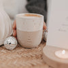 Keramikbecher „Me Time“ mit Herz, Cappuccino und kleiner Discokugel neben einem brennenden Teelicht