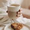 Beiger Keramikbecher „Hab einen tollen Tag“ mit Herz und Kaffee, in einer Hand gehalten