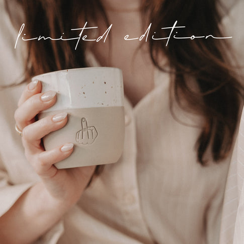 Frau hält einen Limited Edition Keramikbecher in Beige und Weiß mit geprägter Handgeste.
