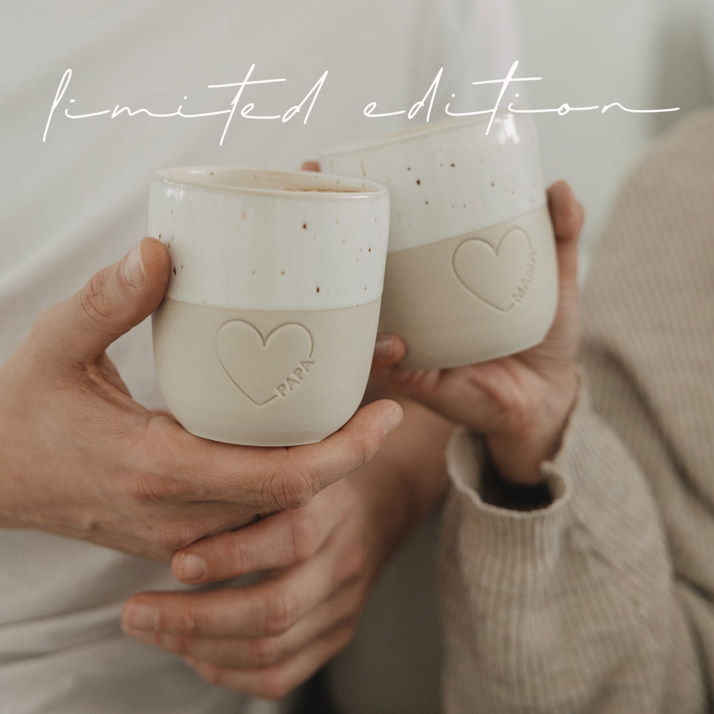 Zwei Keramikbecher Papa und Mama mit Herzmotiv beim Anstoßen, gemütliche Szene, Limited Edition