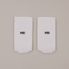 Flachliegende weiße Socken mit „MR“ Schriftzug in minimalistischer Darstellung