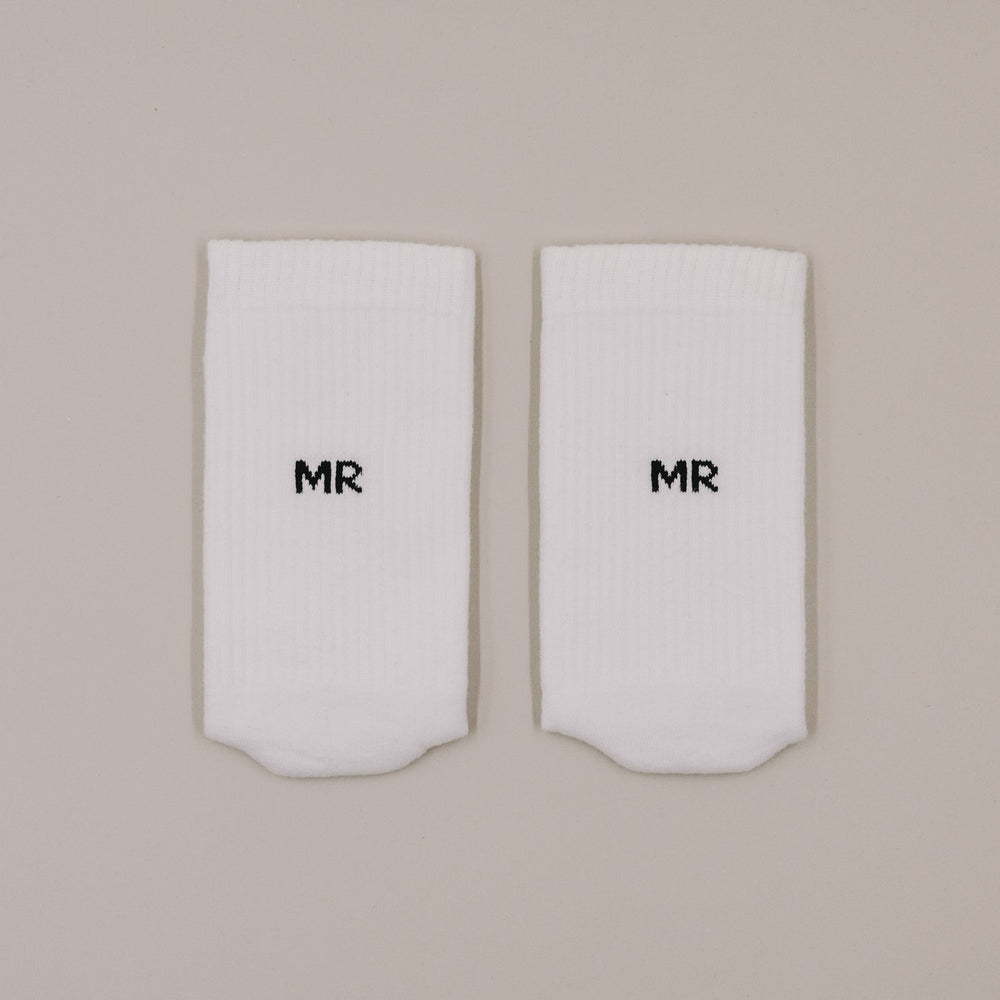 Flachliegende weiße Socken mit „MR“ Schriftzug in minimalistischer Darstellung
