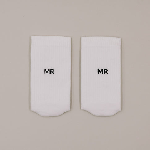 Flachliegende weiße Socken mit „MR“ Schriftzug in minimalistischer Darstellung