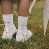 Detailansicht weiße Socken „Schulkind“ mit buntem Schriftzug, getragen auf Wiese