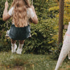Kind auf Schaukel im Garten mit weißen „Schulkind“ Socken und Sneakern