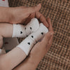 Babyfüße in weißen Socken mit schwarzen Herzen, in Händen gehalten, liebevolle Detailaufnahme