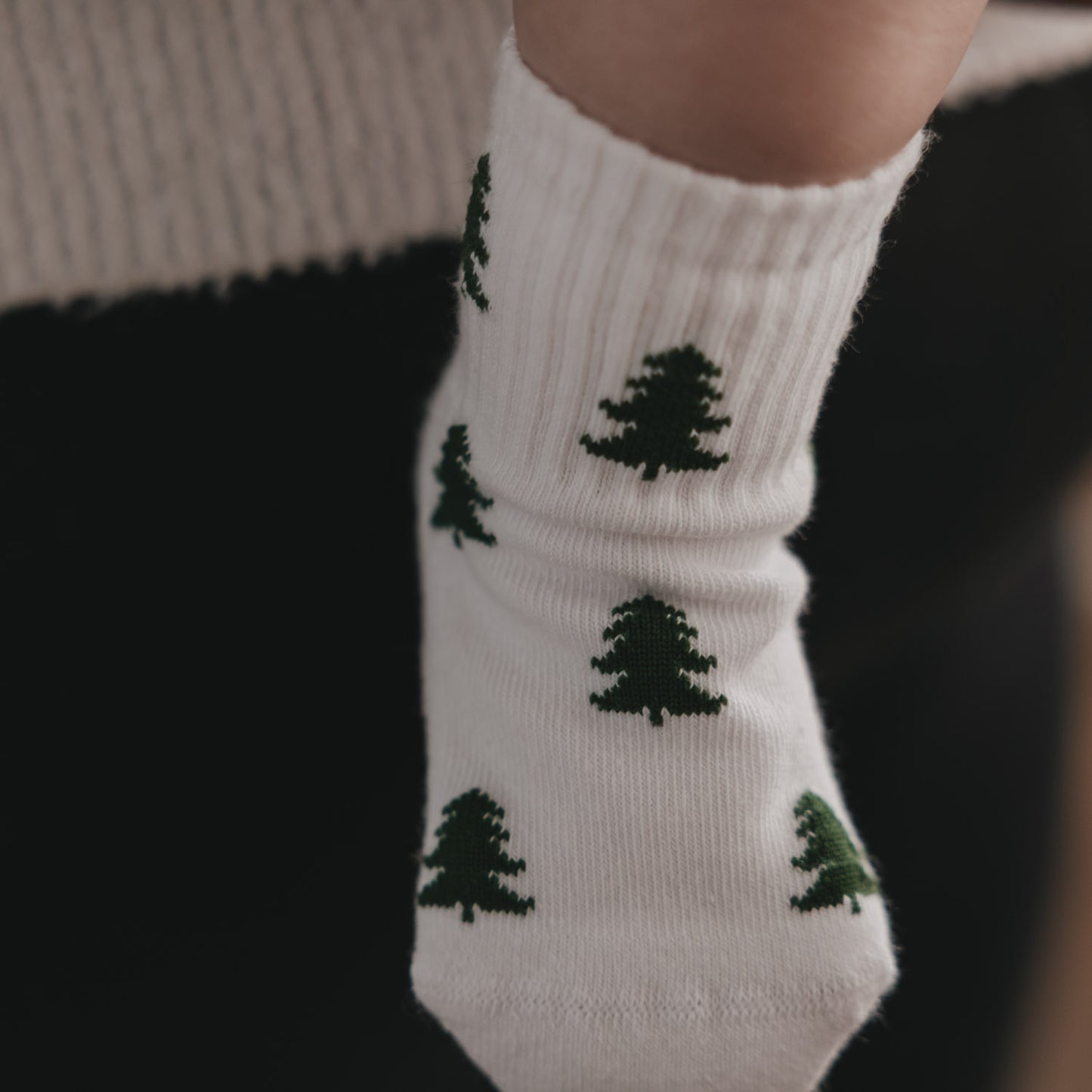 Close-up weiße Baby Socken mit grünen Tannen, gemütliche Winteroptik und weiches Material