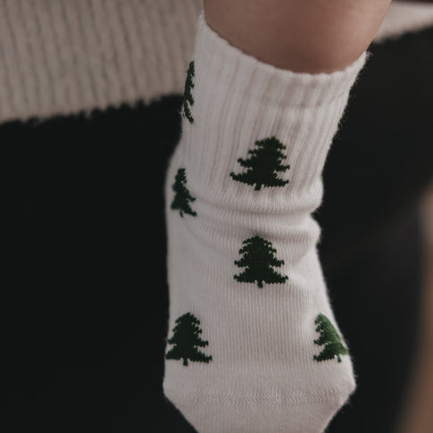 Close-up weiße Baby Socken mit grünen Tannen, gemütliche Winteroptik und weiches Material