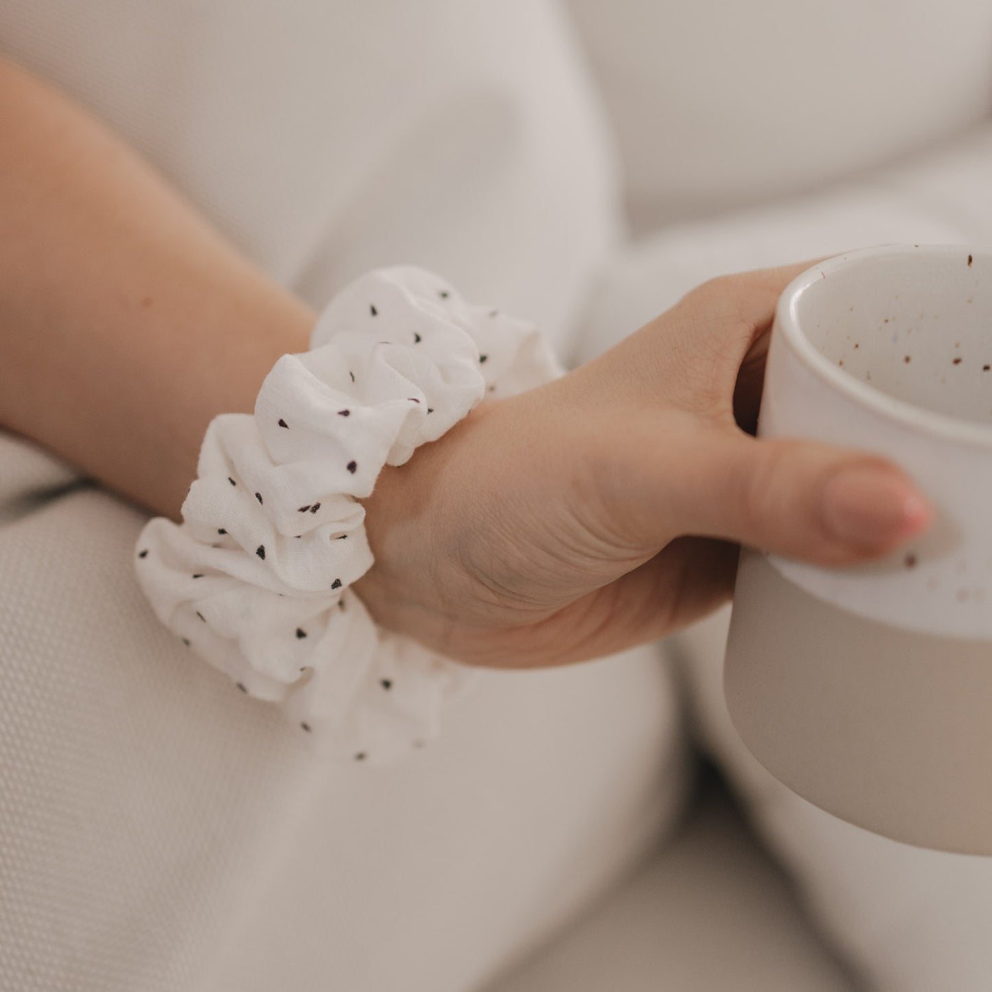 Weißes Scrunchie mit schwarzen Herzen am Handgelenk getragen