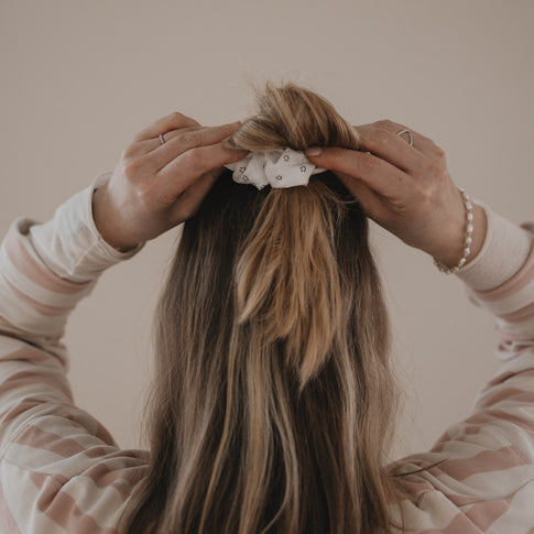 Hände stylen Dutt mit weißem Scrunchie mit Smiley-Muster