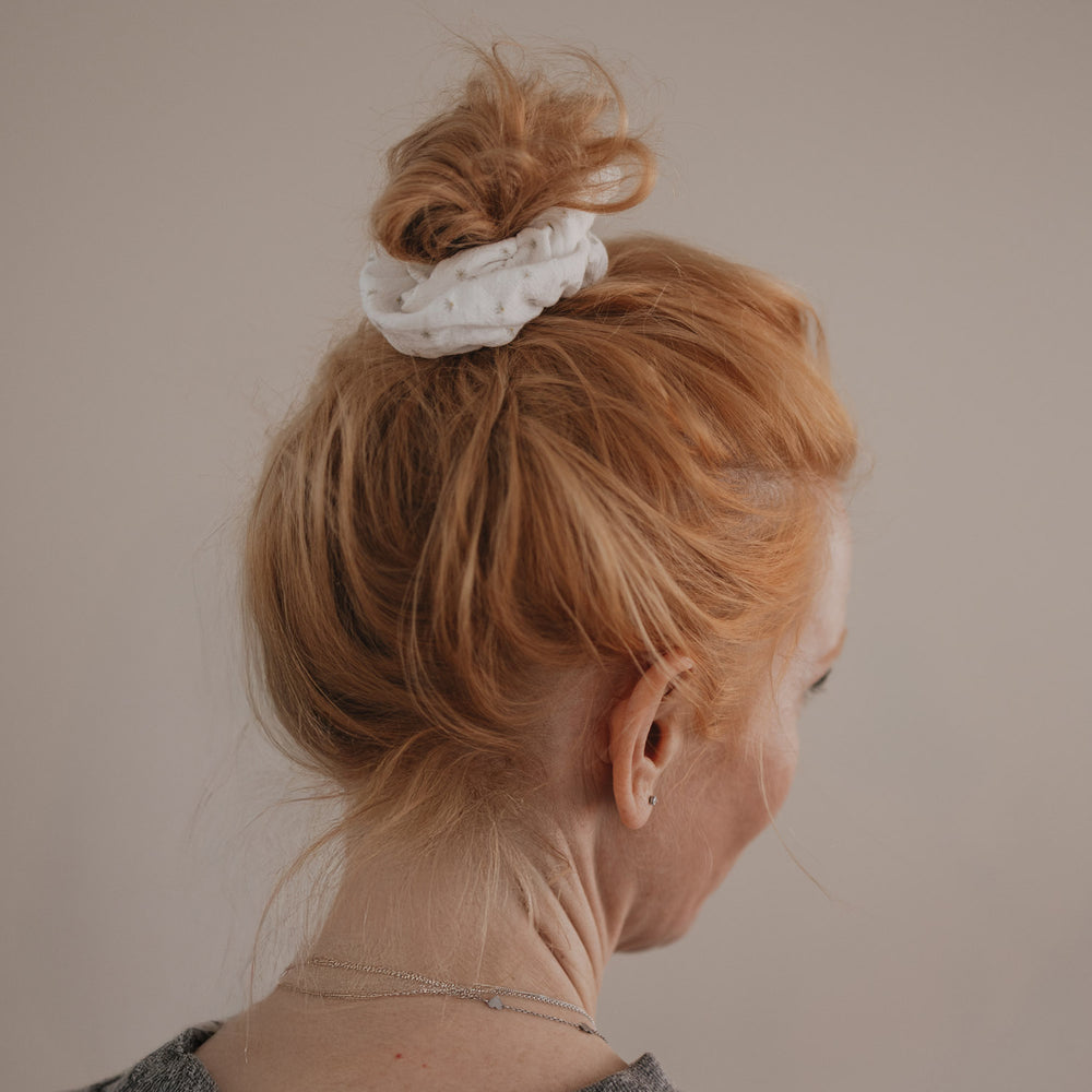 Weißes Scrunchie mit Blumenmuster hält Dutt im roten Haar von hinten