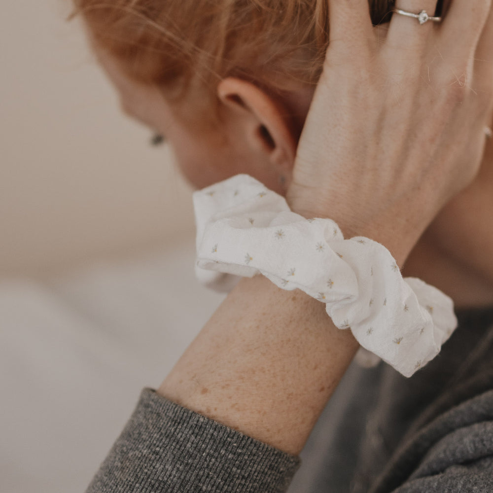 Weißes Scrunchie mit Blumenmuster am Handgelenk getragen