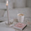 Rosa Streichholzschachtel mit Schriftzug „make a wish“ neben Kerze und Kaffee.