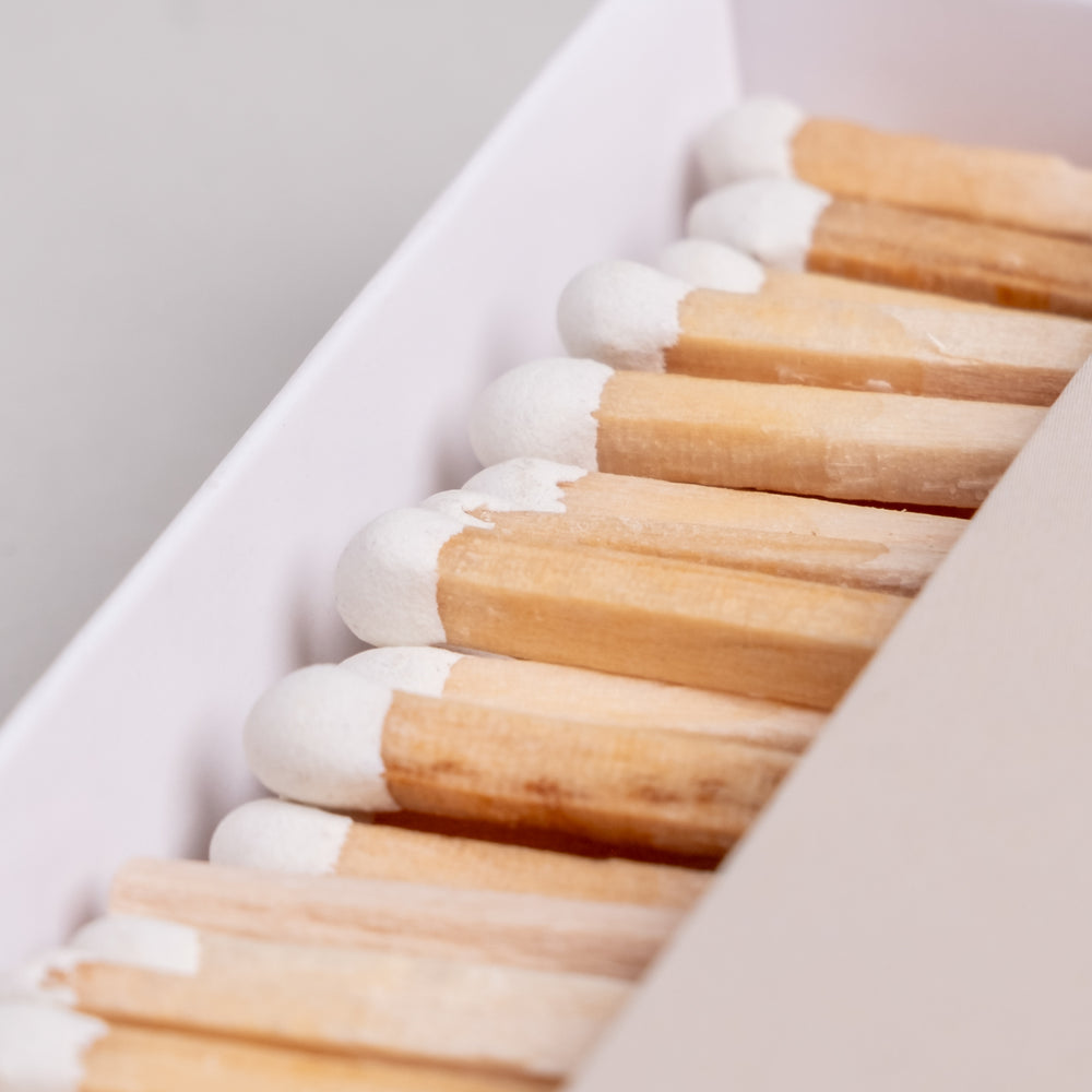 Weiße Streichholzköpfe in naturbelassener Holzoptik in offener Box – dekorative Streichhölzer im Detail.