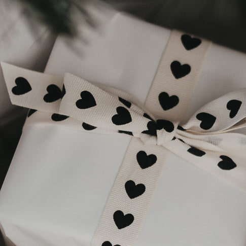 Nahaufnahme Geschenkband mit schwarzen Herzen auf beigem Grund
