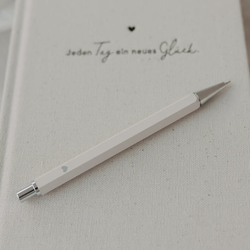 Druckbleistift Creme auf Notizbuch mit feiner Struktur und Herzmotiv.