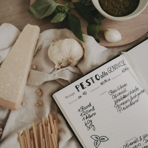 Ausgefüllte Rezeptseite für Pesto im Rezeptbuch, dekoriert mit frischen Zutaten