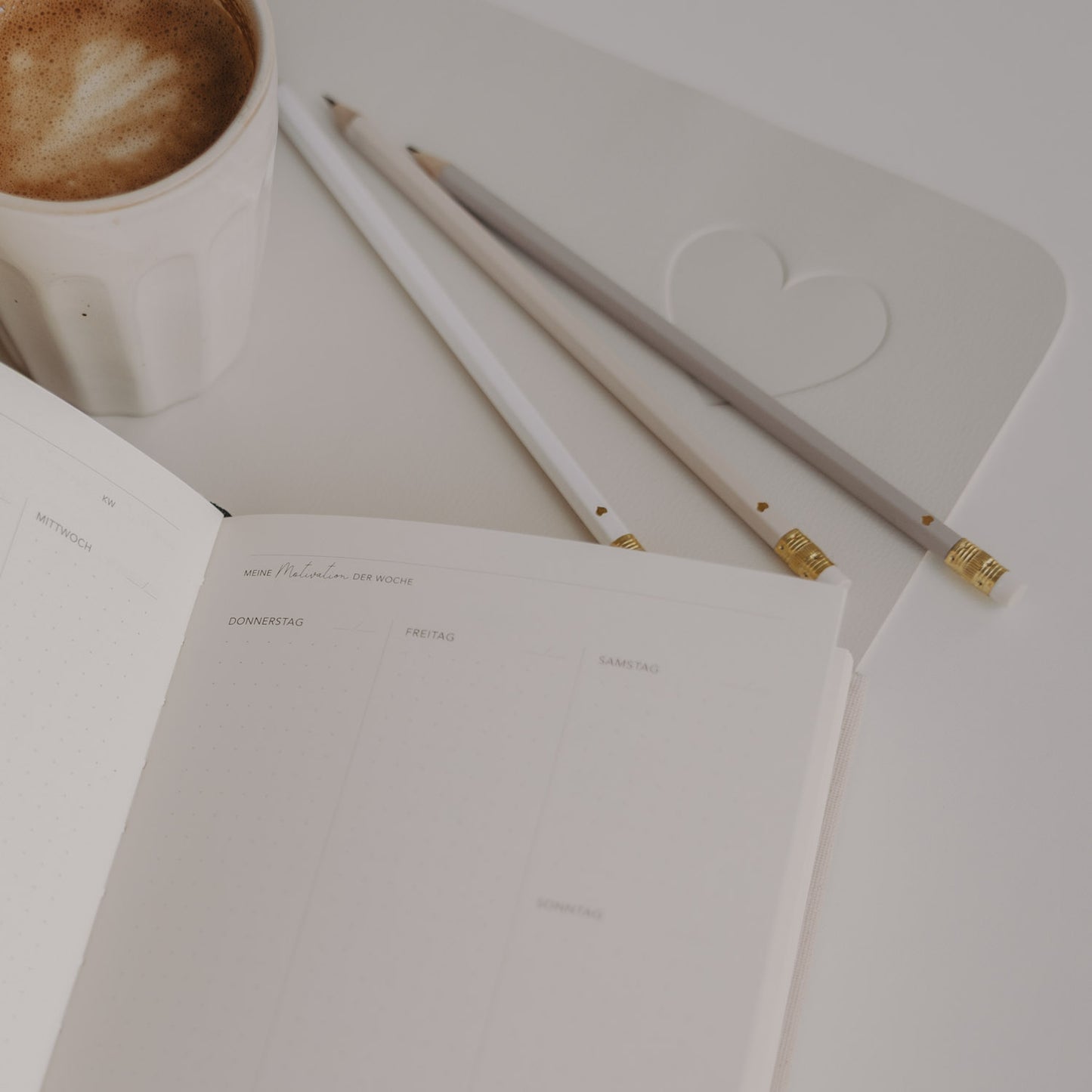 Bleistifte neben Notizbuch und Kaffeetasse auf Schreibtisch